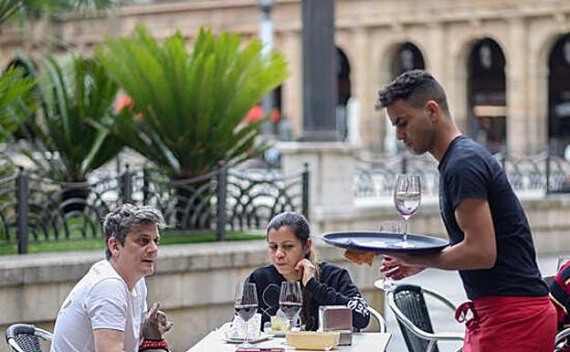 Clientes y camarero en la terraza de un bar. 