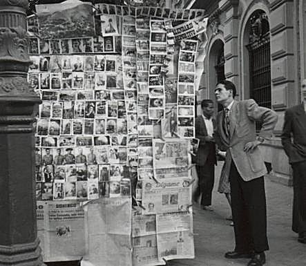 Un hombre observa las fotografías que cuelgan de un Quiosco en la Gran Vía.