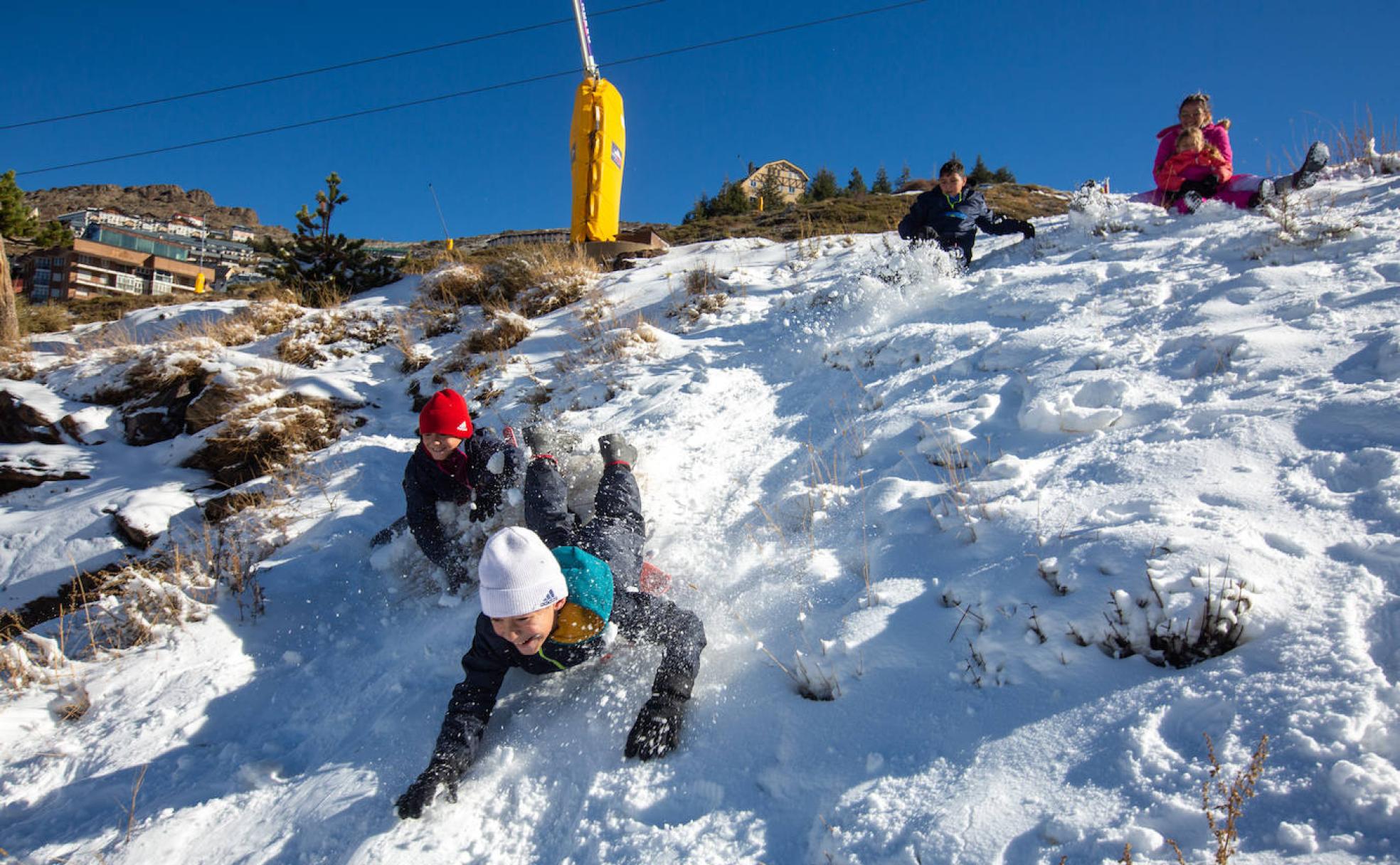 Adonai, Jairo, Ismael y Yarisa se lanzan en trineo por los primeros copos de nieve, este domingo, en Pradollano. 