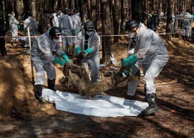 Imagen secundaria 1 - Arriba, un voluntario ucraniano destruye los restos de un tanque en Izium. Abajo, el coronel Safonov e investigadores en una fosa común.