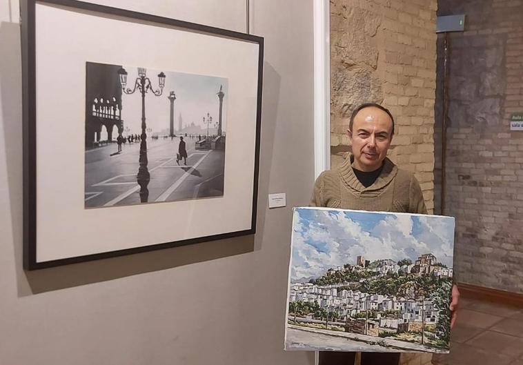 José Domínguez posa en la sala de exposiciones de la Diputación con el cuadro de Martos, realizado 1986, y la imagen de Venecia, una de sus últimas pinturas.