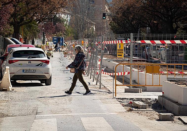 Una vecina cruza la zona de obras en la carretera de Málaga.