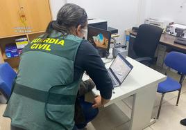 Agentes de la Guardia Civil revisando documentos informáticos.