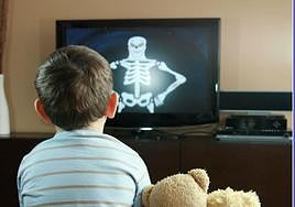 Un menor ve la tele acompañado de dos peluches.