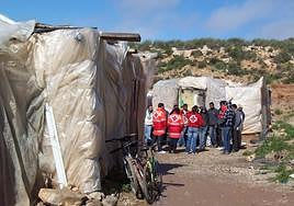 Inmigrantes ilegales en un poblado chabolista reciben la asistencia de personal de Cruz Roja.