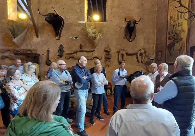 Imagen principal - Arriba: Los socios de ATA atienden a las explicaciones de Samuel Flores. En el centro, algunos visitantes observan a los toros en el campo. Abajo, Samuel Flores y Julio Gómez se intercambian detalles.