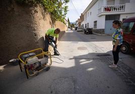 La alcaldesa de El Valle observa cómo un operario abre la calle para buscar la fuga de agua en Melegís.