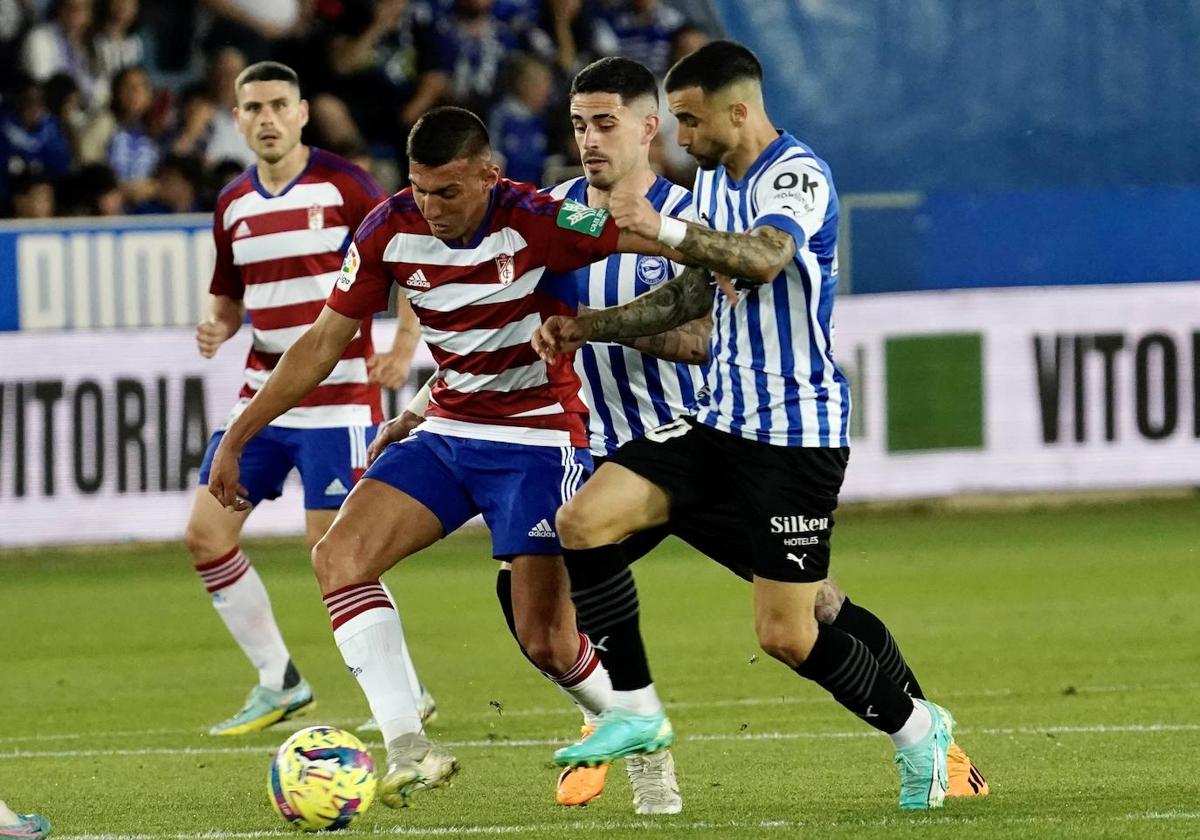 Myrto Uzuni trata de escapar de dos futbolistas.