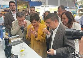 La ministra, Isabel Rodriguez, huele el aceite de oliva en uan copa de cata en el estand de Diputación, junto al alcalde Julio Millán y el presidente de la Diputación Francisco Reyes.