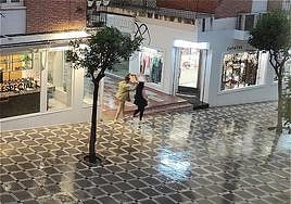 Una pareja se cubre con un cartón sorprendidos por la lluvia.