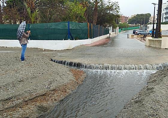 Una persona hace una fotografía de la lluvia caída en el Paseo Marítimo de Aguadulce.