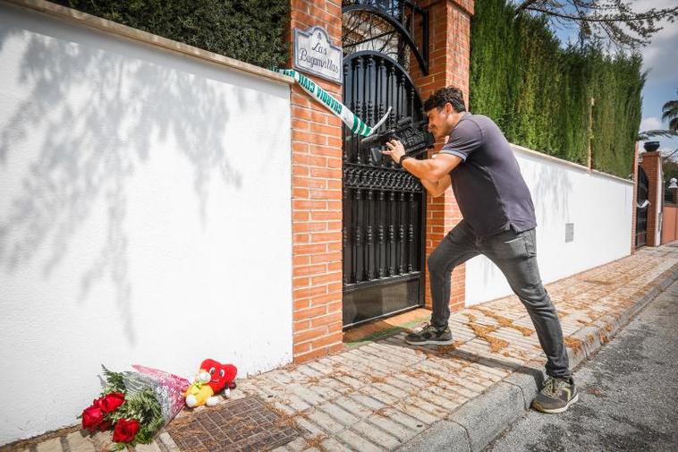 Un cámara, junto a las flores y los peluches depositados junta a la casa en la que ocurrió el crimen