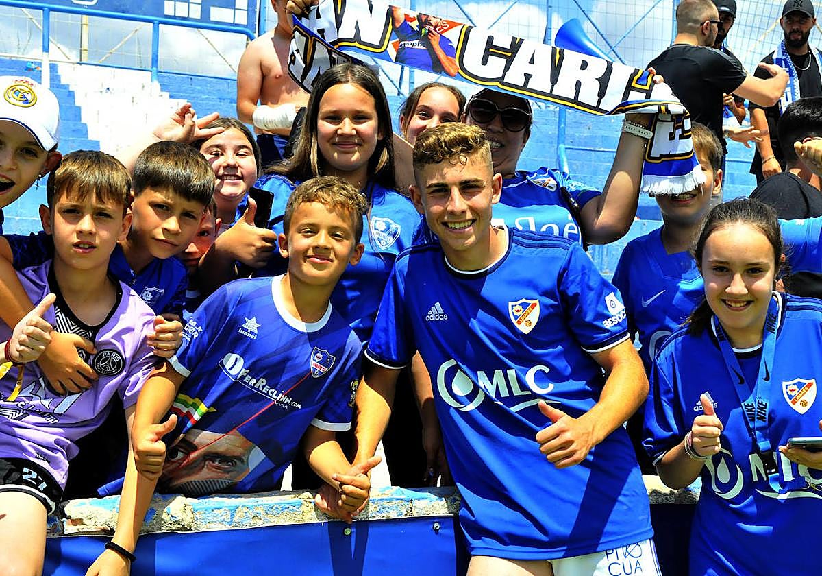 Fermín López posando con un grupo de niños en la grada, al finalizar un partido en Linarejos.