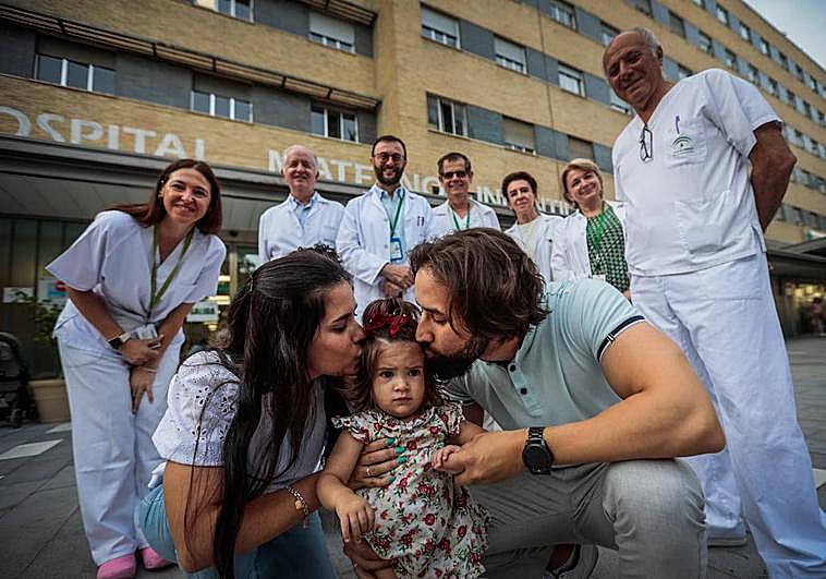 En primer plano, la pequeña Victoria junto a sus padres. Detrás, los profesionales sanitarios del Hospital Materno Infantil.