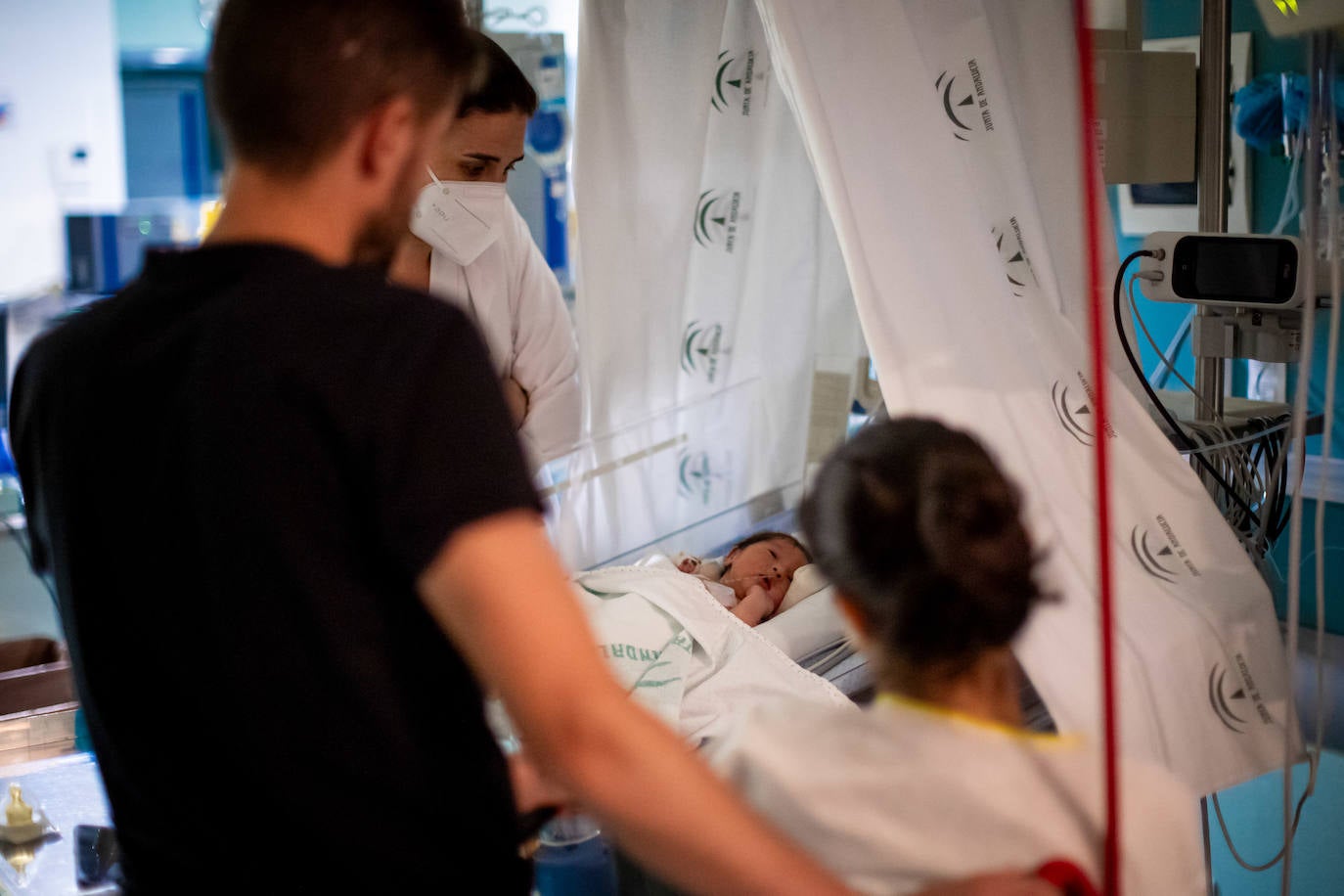 Imagen principal - En la primera imagen, Pili y Jairo, de espaldas, observan a su Martina. En la segunda, Ana y su prima Noelia, matrona que la ayudará en el parto. En la última, una cesárea en el Clínico.