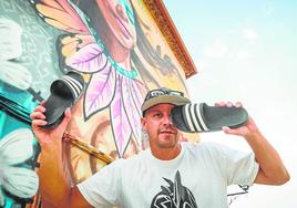 El grafitero Badi Coloreando juega con sus chanclas ante el precioso mural que ha pintado en el Ayuntamiento de Nívar.