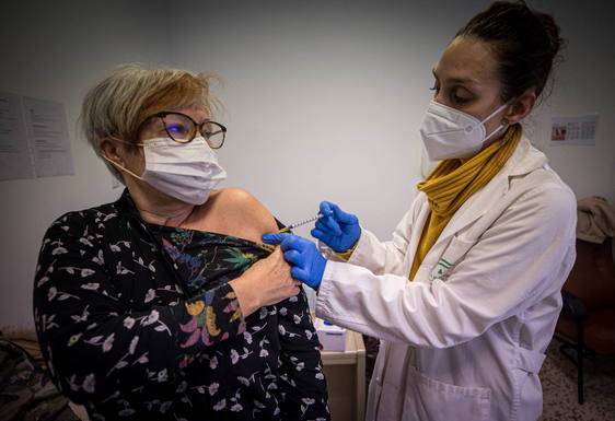 Una profesional sanitaria vacuna a una mujer contra la covid.