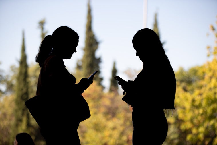 Dos alumnas de la Facultad de Educación leen un grupo de whastapp.