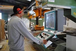 Un alumno de la Escuela de Mármol manipulando una máquina de corte de piedra natural.