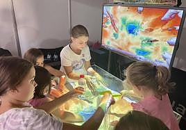 Unas niñas juegan con un simulador geomático de realidad aumentada.