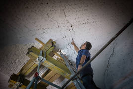 Un técnico muestra las grietas con forma de cruz provocadas por los terremotos de 2021 en las Caballerizas del Hospital Real.