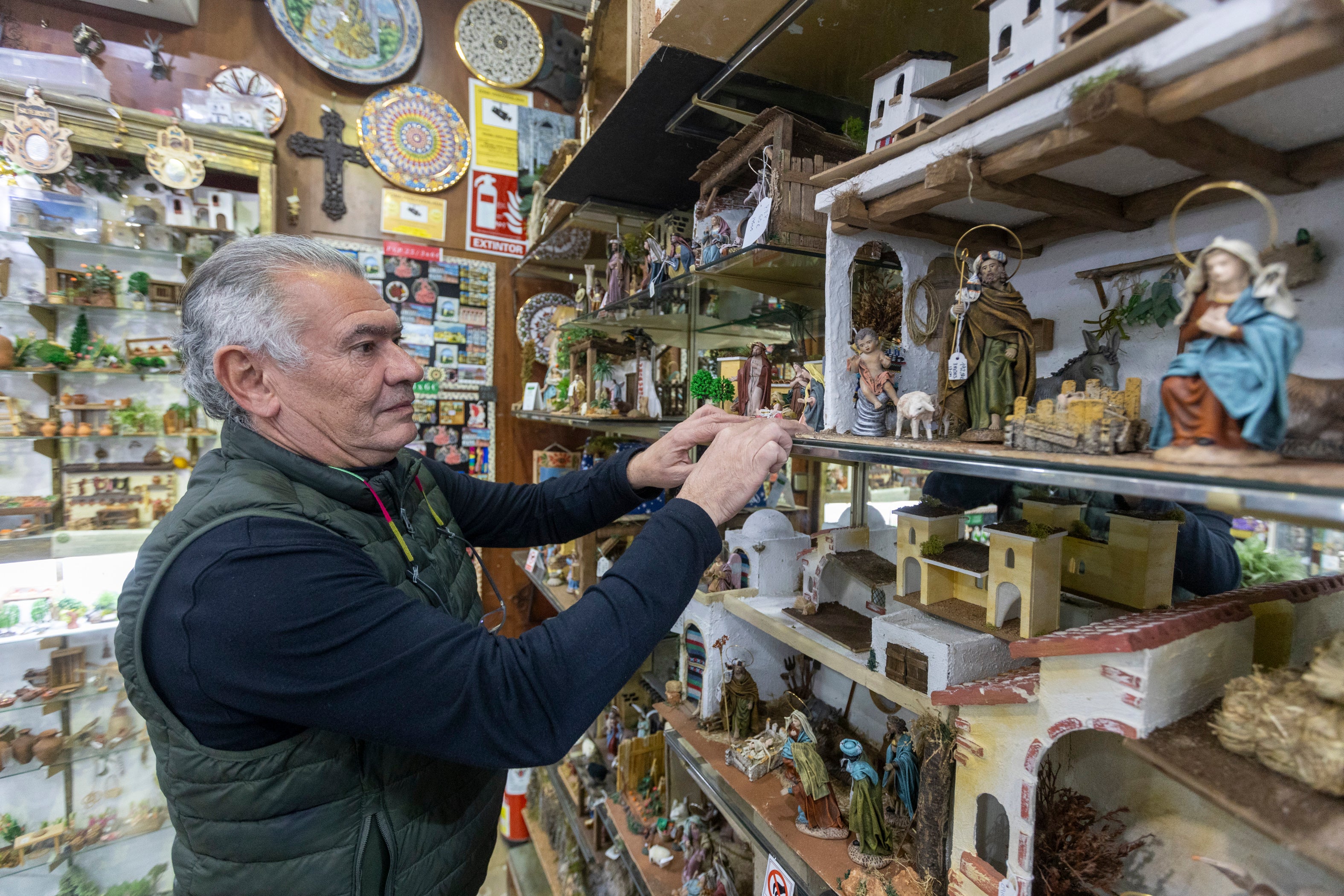 Miguel López Mariscal monta sus piezas de belén en los estantes de su tienda de la Alcaicería.