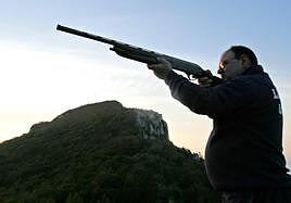 Imagen de archivo de un cazador disparando una escopeta.