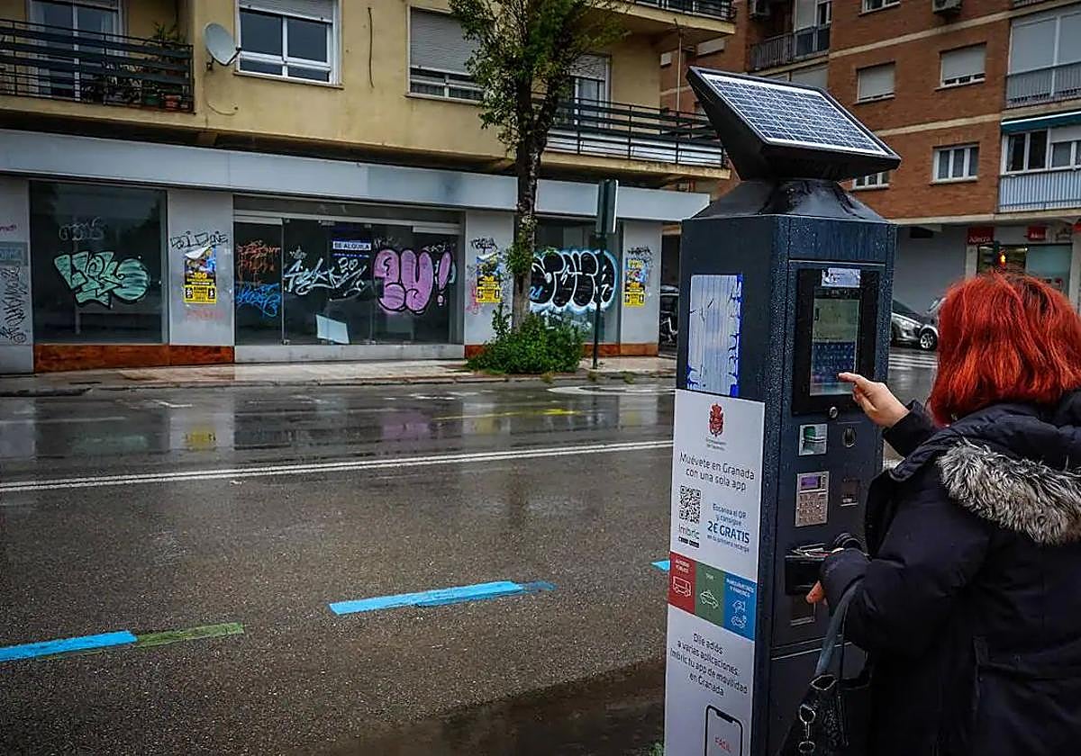 Una mujer saca el ticket de la zona azul en la calle Arabial.