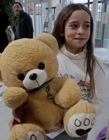 Imagen secundaria 2 - Arriba, Martín delante de su regalo. Abajo, acarreando la silla y una alumna con el peluche mascota. 
