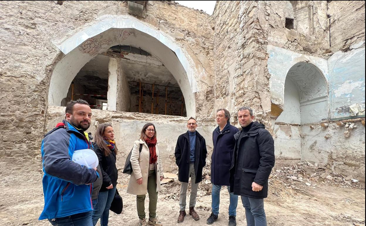 Visita municipal a las ruinas de la iglesia de San Miguel, con arco apuntado al fondo y ménsula encima. 