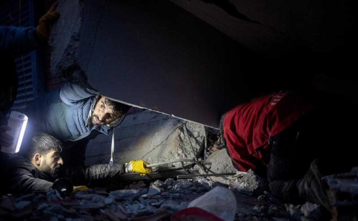 Varias personas intentan ayudar a las víctimas en el lugar donde se derrumbó un edificio tras un terremoto en Diyarbakir, Turquía. 