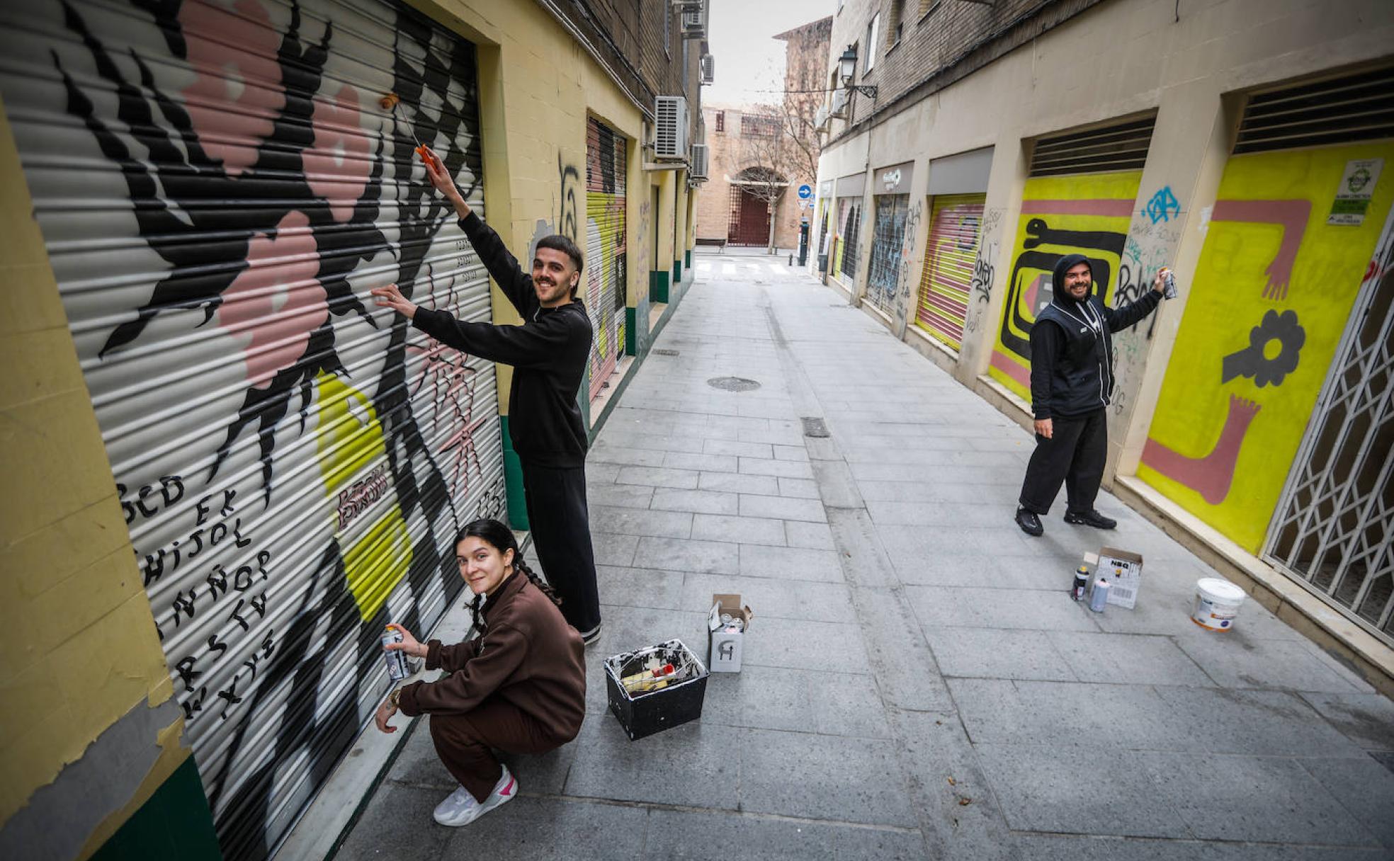 Sara Ocampo, PabloTorralba y Daniel Martín, frente a los murales de Mano de Hierro.