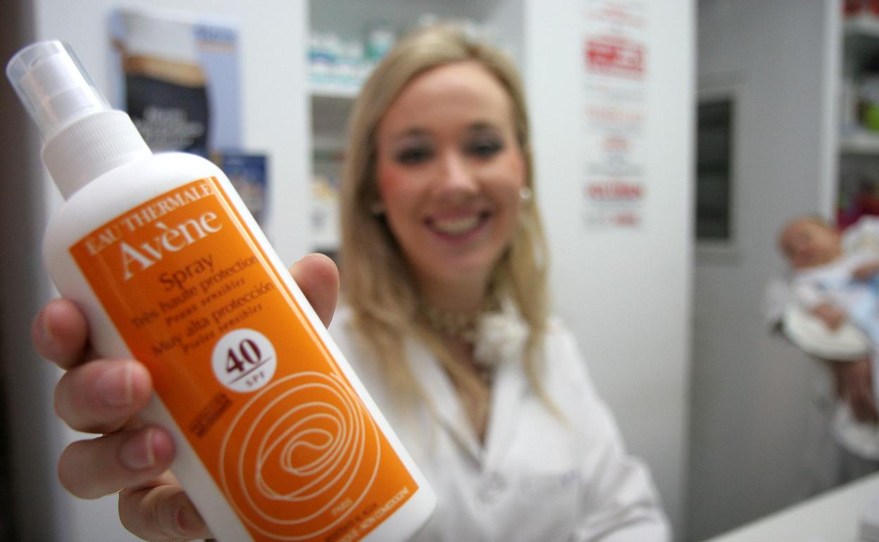 Una farmacéutica muestra una crema solar. 