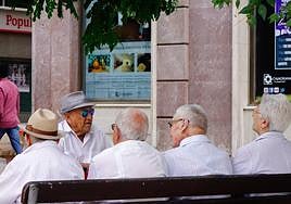 Varios pensionistas conversan en un banco.