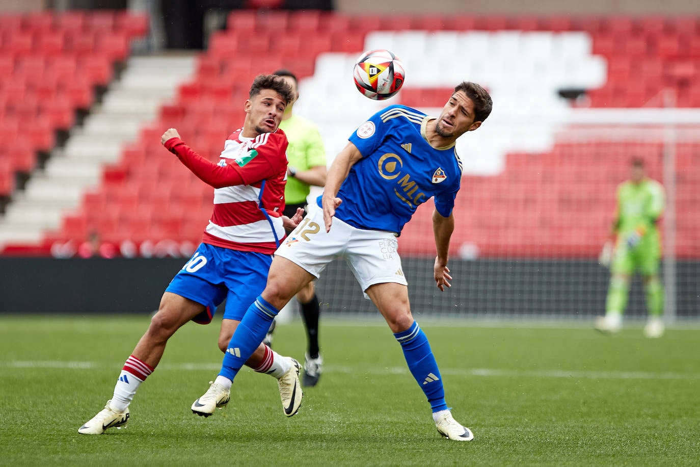 Disputa de un balón en los Cármenes entre jugadores del Recreativo Granada y el Linares Deportivo.