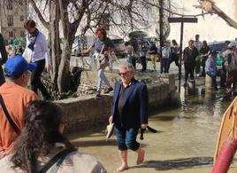 Un turista cruza descalzo el puente que se ha inundado.