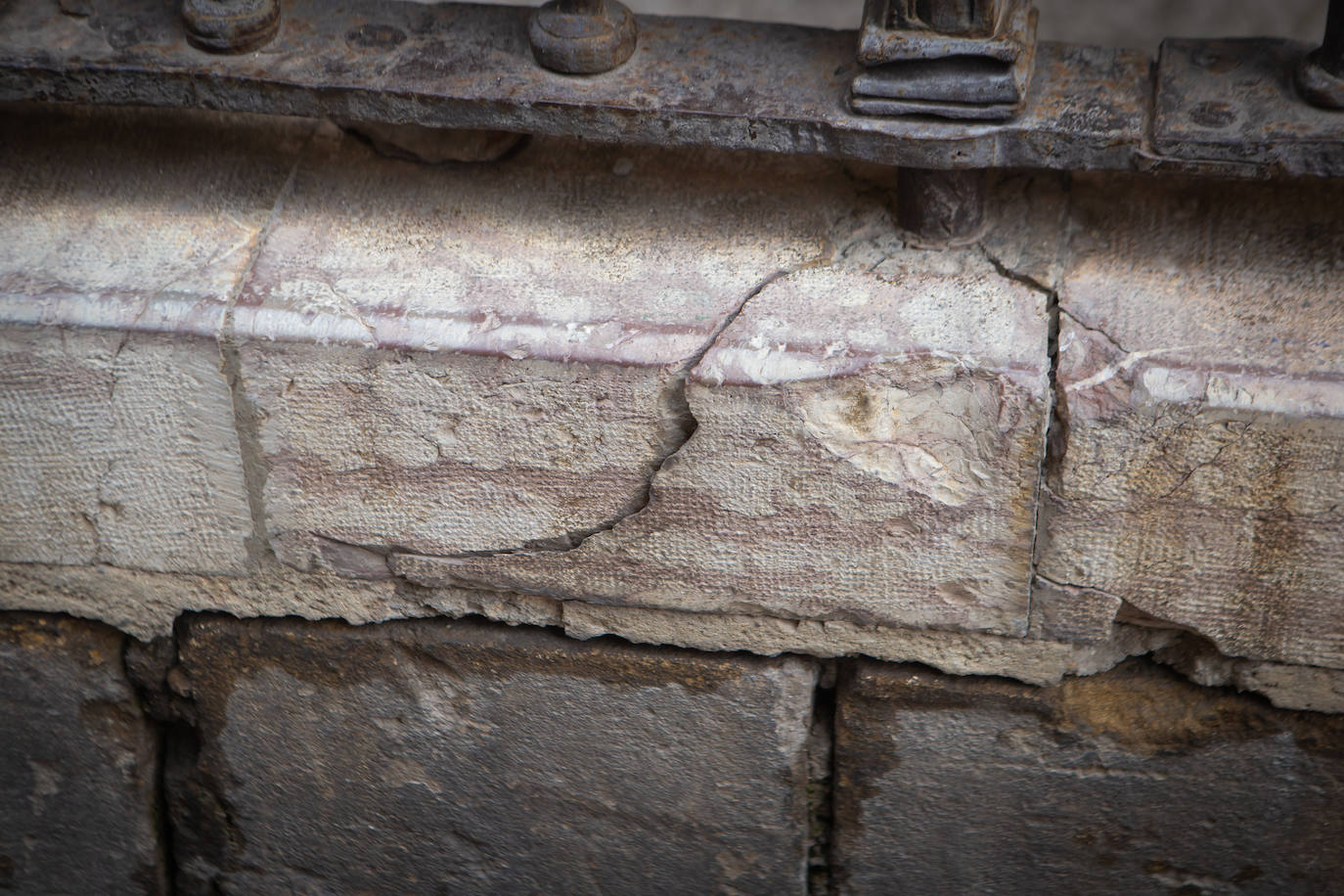 Fisuras y roturas de material pétreo como consecuencia de acciones mecánicas debidas al movimiento y las solicitaciones que provoca el anclaje de una verja monumental.