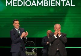 El presidente Juanma Moreno aplaude a Manuel Titos tras hacerle entrega de la Medalla de Oro al Mérito Medioambiental.
