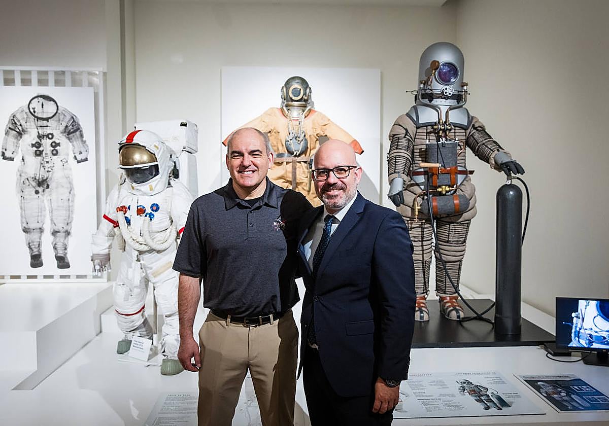 Carlos García-Galán, VI Premio Viajero del Tiempo, junto a Amador Carmona, director comercial de CaixaBank para Granada y Jaén, posan junto a trajes de astronauta expuestos en el Parque de las Ciencias.