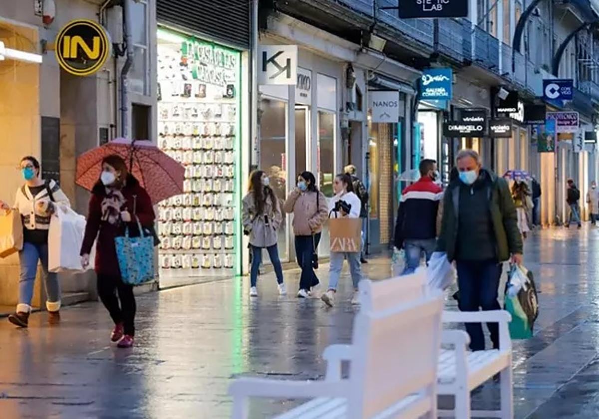 Varias personas pasean en una calle comercial.