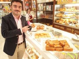 Alejandro Cano, encargado de La Dulce Alianza, sostiene un rosco frito ante apetitosas bandejas de leche frita y las populares torrijas.