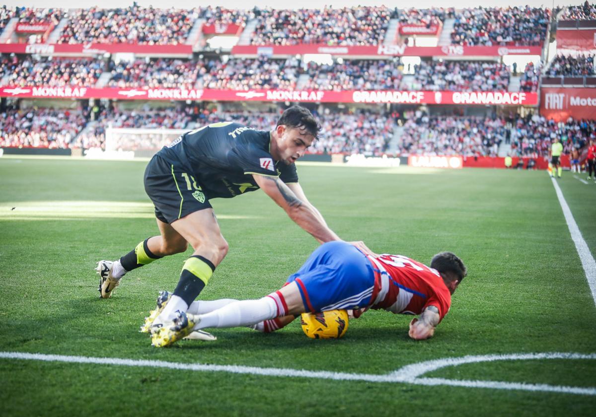 Carlos Neva cae al césped en un lance con Marc Pubill durante el partido entre Granada y Almería el pasado mes de febrero en Los Cármenes.