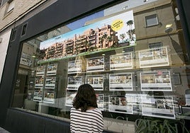 Una persona observa en una inmobiliaria pisos y casas, de archivo.