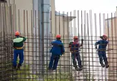 Trabajadores de la construcción realizan trabajos en altura en una obra portando el arnés obligatorio de seguridad.