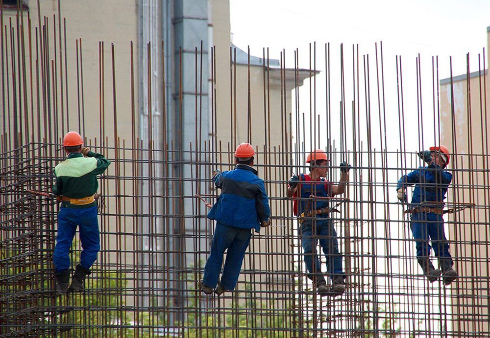 Trabajadores de la construcción realizan trabajos en altura en una obra portando el arnés obligatorio de seguridad.