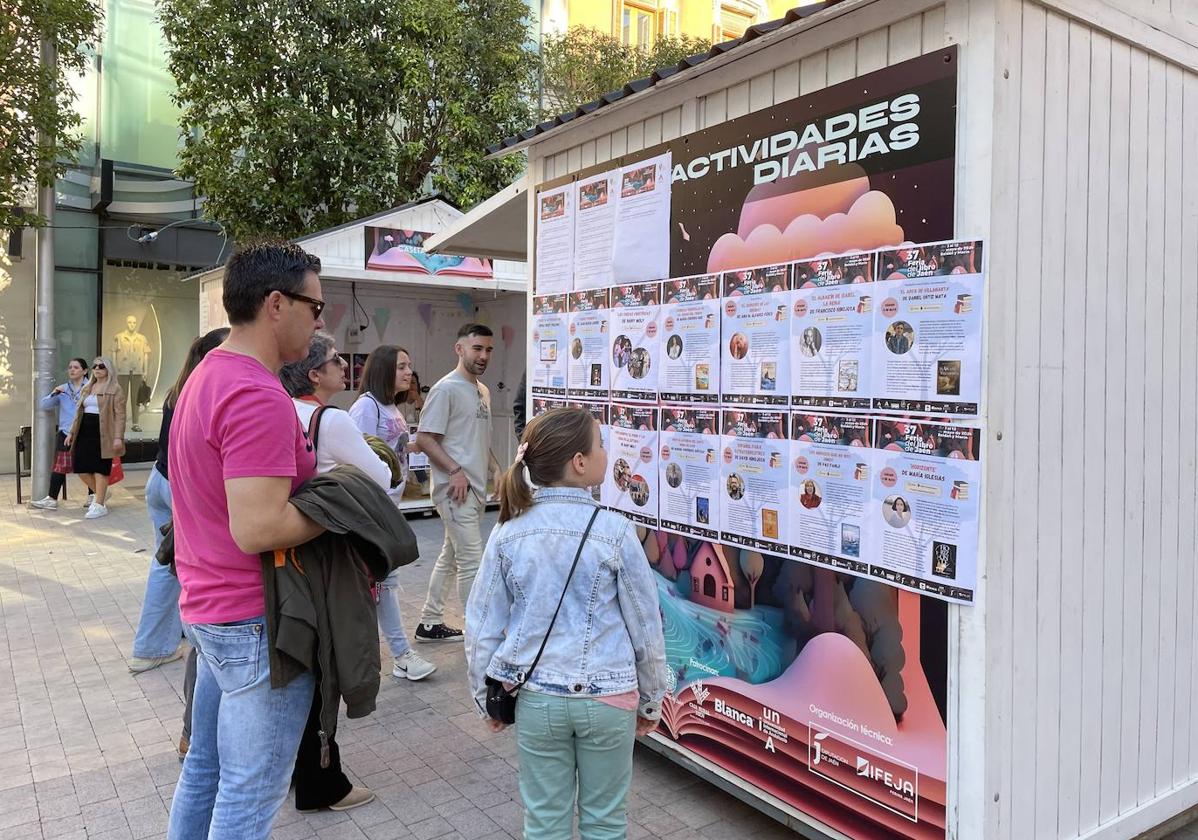 una familia mira la programación diaria de actividades de la Feria del Libro.