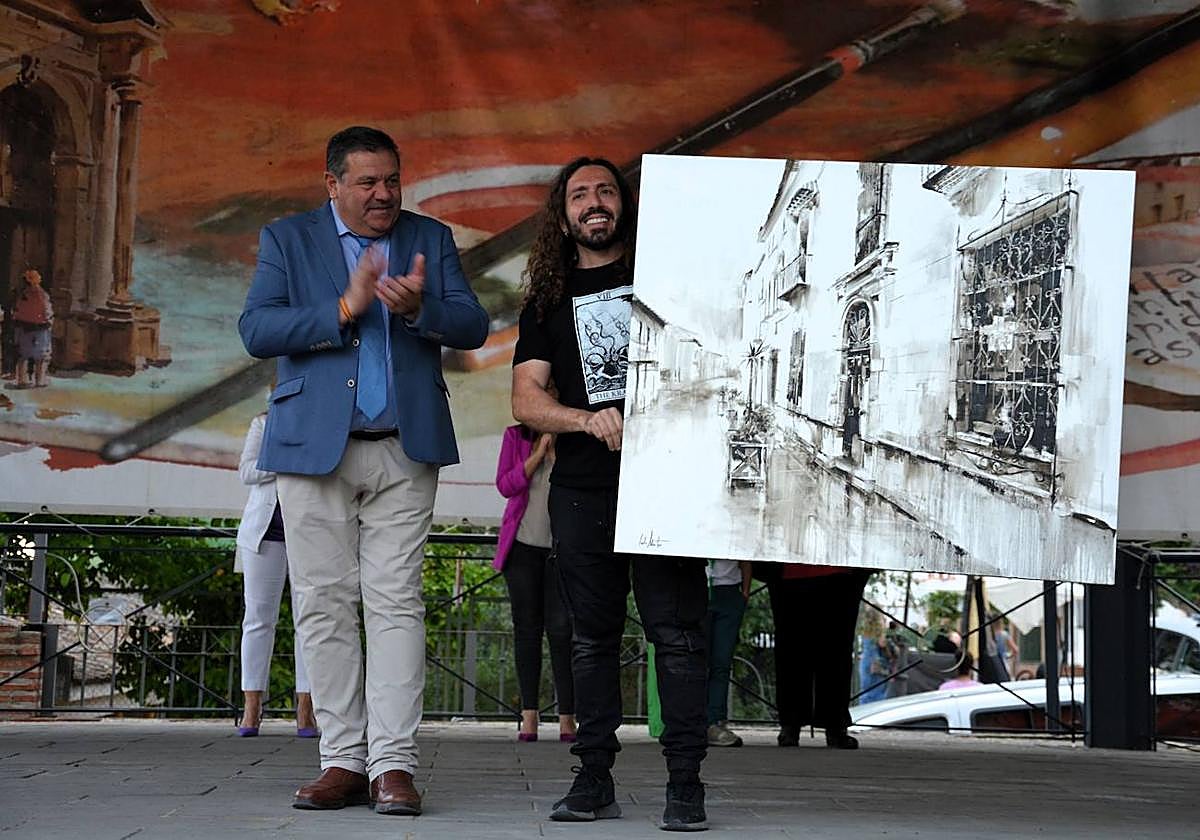 El ganador Carlos Montoro sostiene la obra.