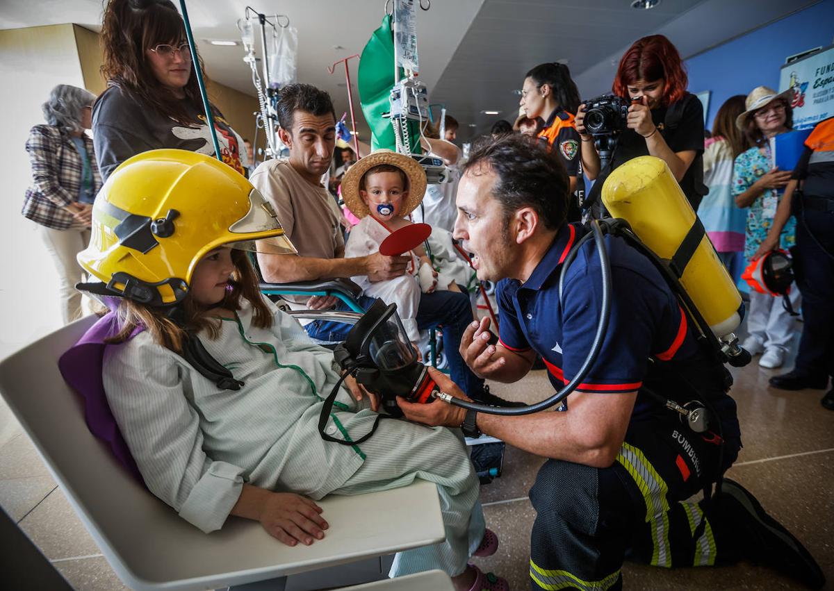 Imagen secundaria 1 - Víctor hace la señal de triunfo con su casco de bombero. Los niños y niñas ingresados se lo pasaron estupendamente.