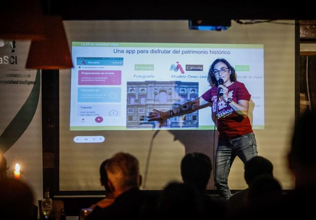 Rosana Montes habla de inteligencia artificial en el escenario de la sala, iluminada con velas.