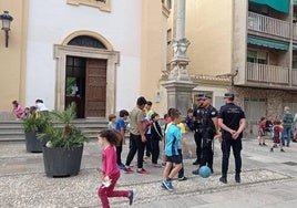 Una patrulla de la Policía Local conversa con unos chiquillos en la entrada de la iglesia de la plaza de Gracia.